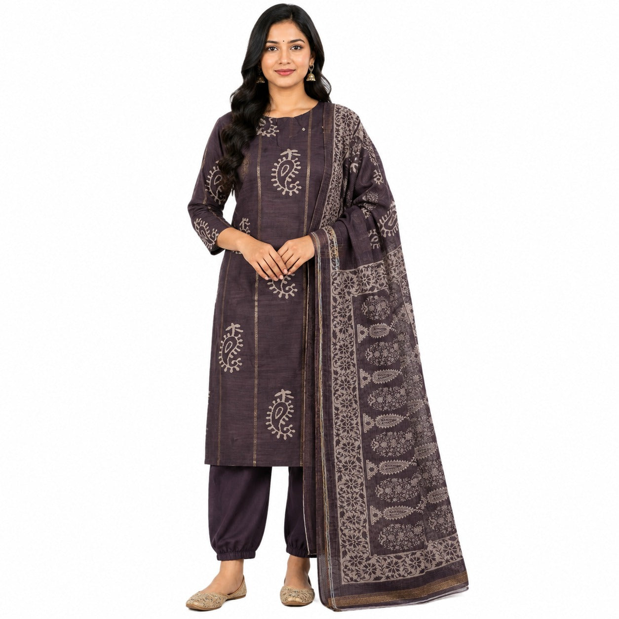 A woman modeling a dark purple three-piece salwar kameez suit with beige block prints, consisting of a long kurta, matching trousers, and a dupatta, set against a plain white background.